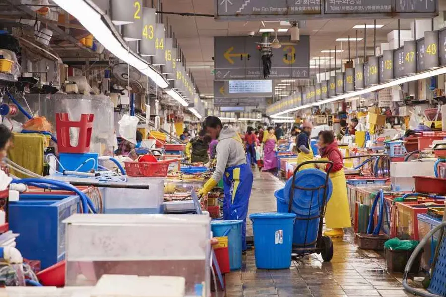 Indoor live-fish hall at Jagalchi Market with tanks, stalls, and working vendors