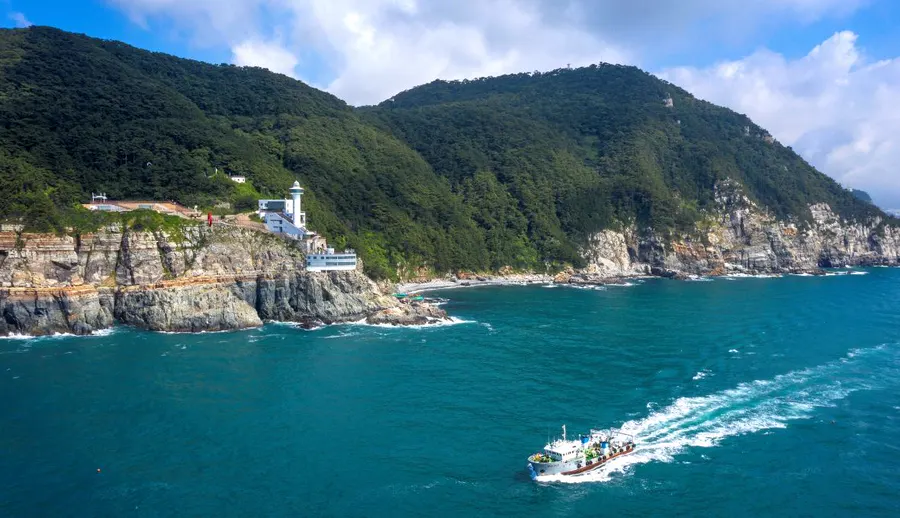 Taejongdae wave-cut cliffs, Yeongdo Lighthouse, forest and a sightseeing boat off the coast