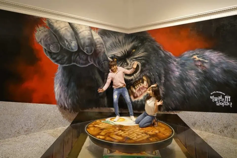 Visitors posing in a 3D gorilla optical-illusion exhibit at Alive Museum Jeju