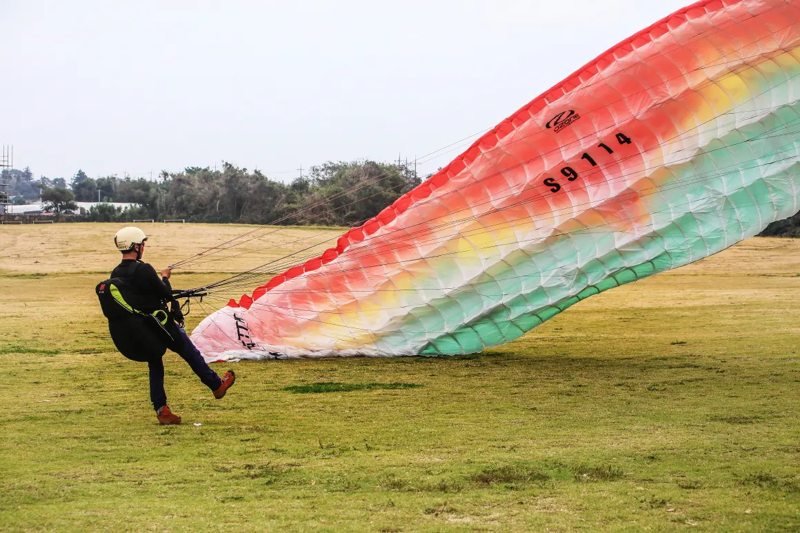 Paragliding pilot preparing a canopy on a Jeju grass launch field