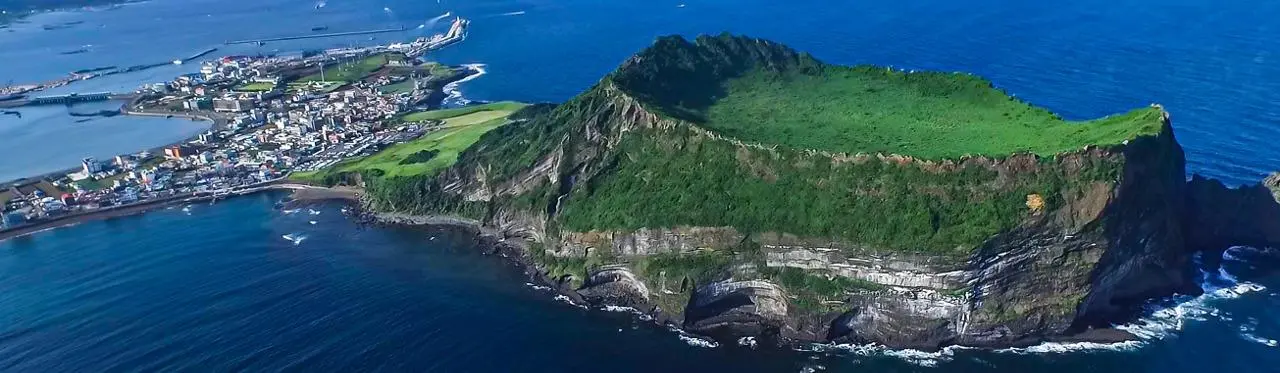Seongsan Ilchulbong volcanic cone rising above the northeast Jeju coast