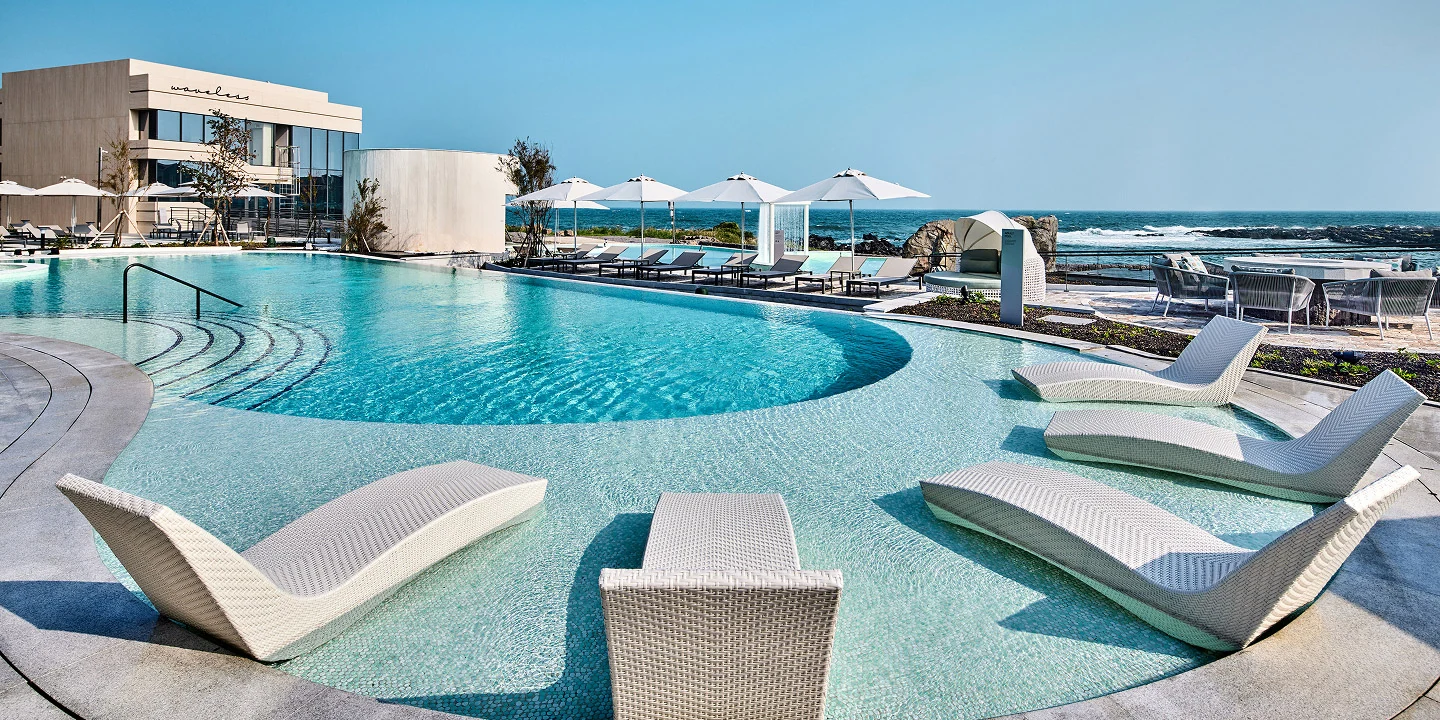 Outdoor pool and loungers beside the sea at a Jeju resort