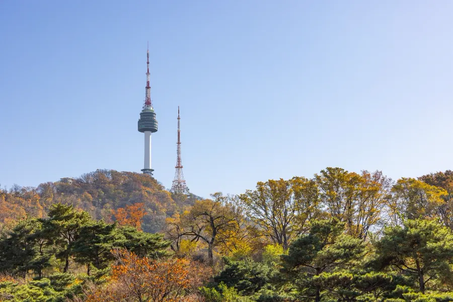 N Seoul Tower and a broadcast mast above the wooded ridge of Namsan